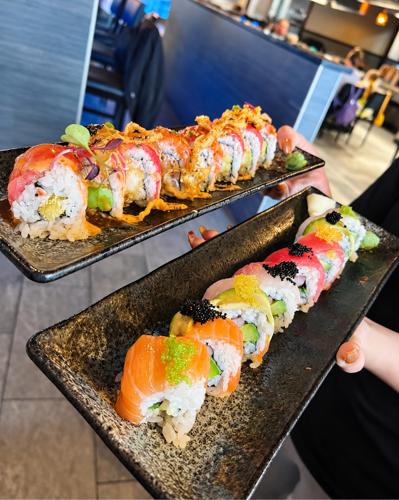 Two signature rolls held up on dark plates at Nori
